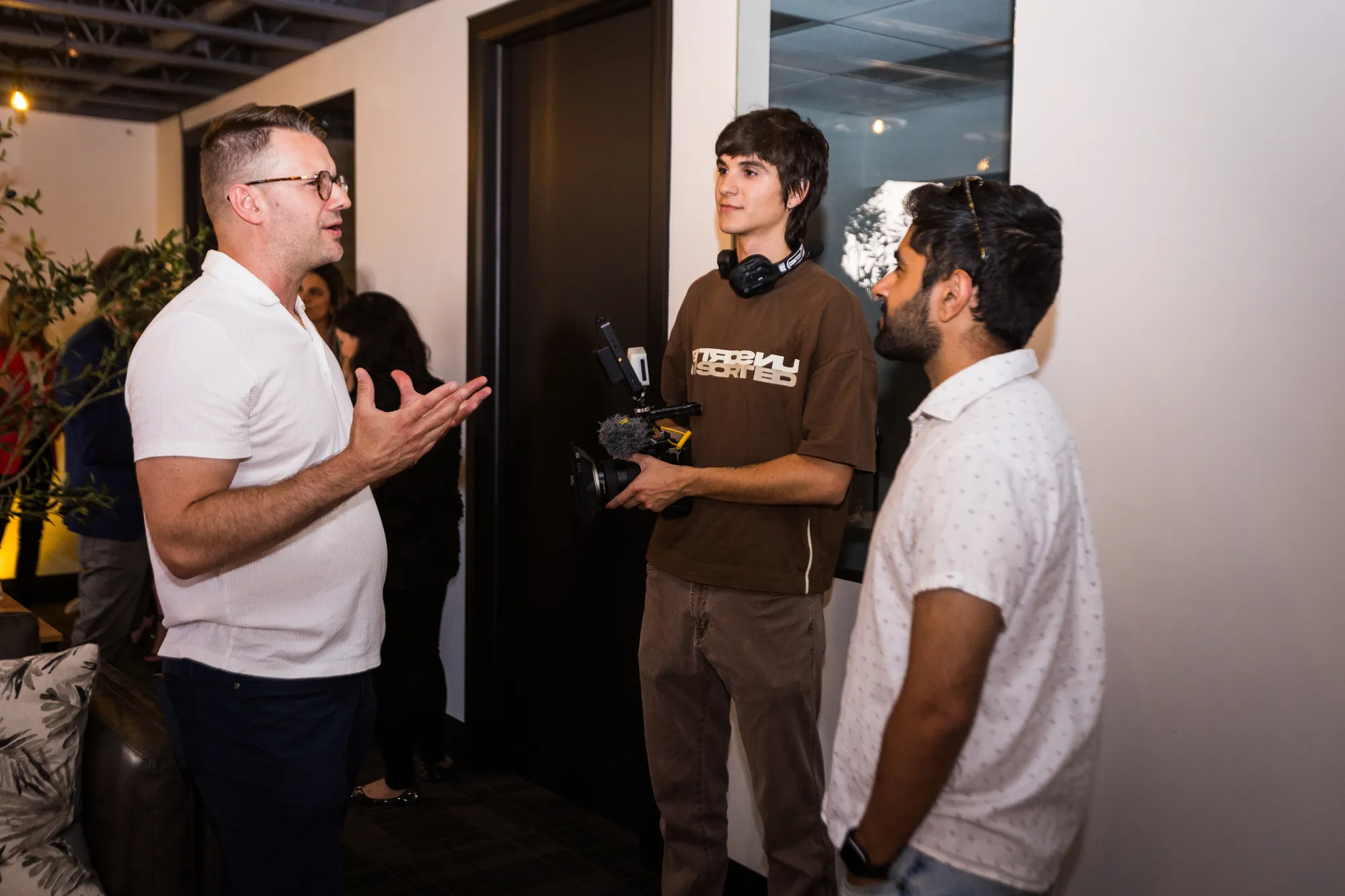 Three guests in conversation at a Creator Lounge event, one holding a camera rig
